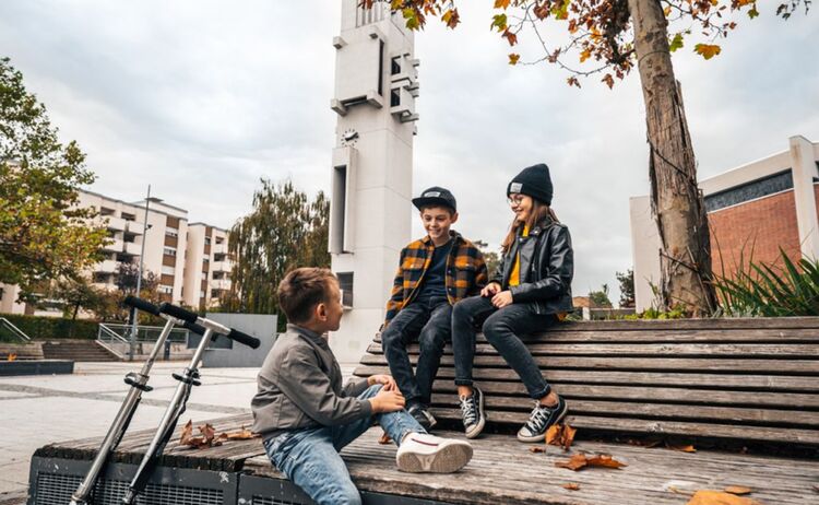 Zwei Jungen und ein Mädchen sitzen am Sartrouville Platz auf einer Bank und unterhalten sich. : Zum Vergrößern auf Bild klicken