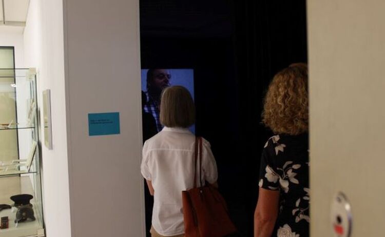 Besucher schauen einen Film zur Ausstellung: Zum Vergrößern auf Bild klicken