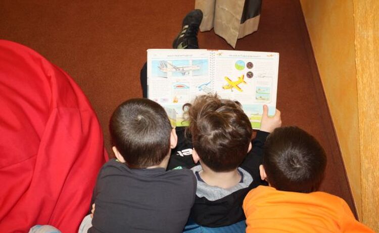 Drei Grundschulkinder lesen ein Buch im Haus des Buches: Zum Vergrößern auf Bild klicken