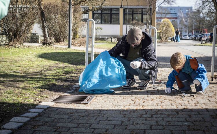 Ein Mann und ein Kind sammeln beim Rama Dama Müll auf: Zum Vergrößern auf Bild klicken