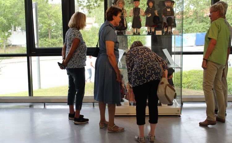 Besucher vor der Vitrine mit Trachtenpuppen: Klick öffnet eine vergrößerte Ansicht