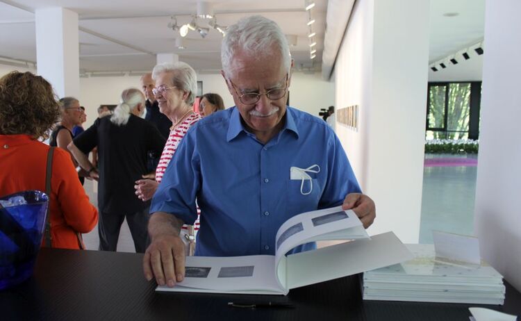 Besucher beim Durchblättern des Ausstellungskatalogs: Klick öffnet eine vergrößerte Ansicht