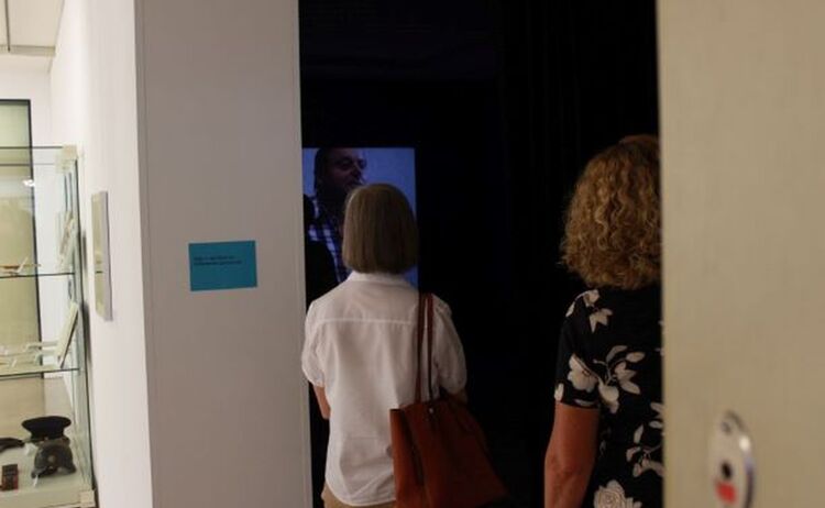 Besucher schauen einen Film zur Ausstellung: Klick öffnet eine vergrößerte Ansicht