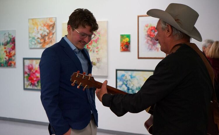Joe Riedl begleitete die Eröffnung mit Gitarre und Gesang, hier mit einem begeisternden Zuhörer: Zum Vergrößern auf Bild klicken