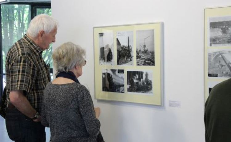 Zwei Besucher betrachten die Bilder der Ausstellung Ein Kanal entsteht: Klick öffnet eine vergrößerte Ansicht