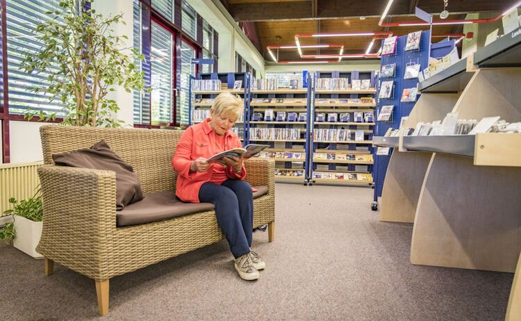 Eine Frau sitzt auf einer Bank im Film- und Musikbereich im Haus des Buches: Zum Vergrößern auf Bild klicken