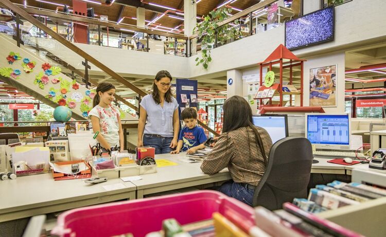 Familie beim Bücher ausleihen an der Empfangstheke: Zum Vergrößern auf Bild klicken