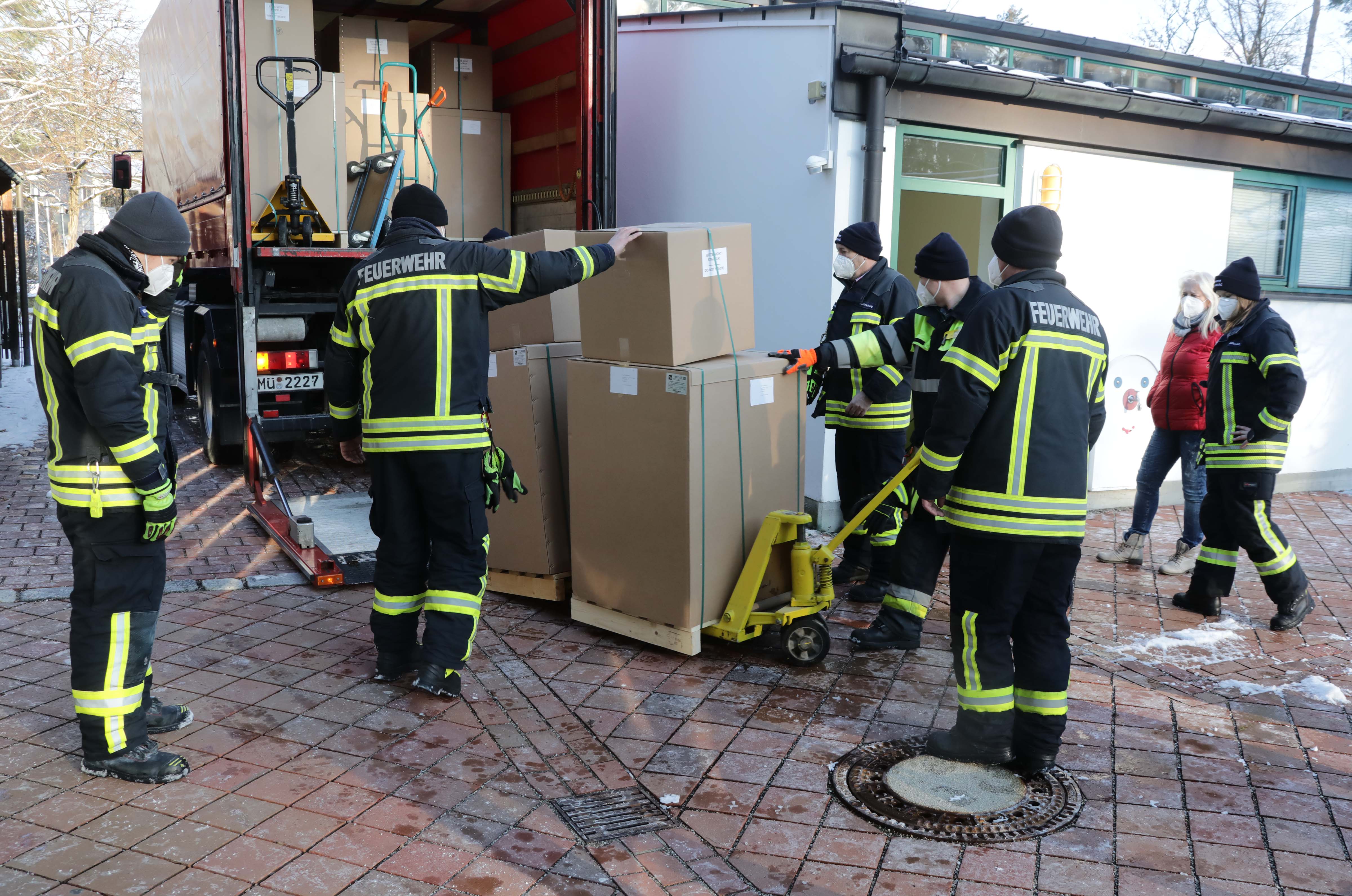 Mitglieder der Freiwilligen Feuerwehr Waldkraiburg bringen die Lieferung der Luftfiltergeräte zum LKW