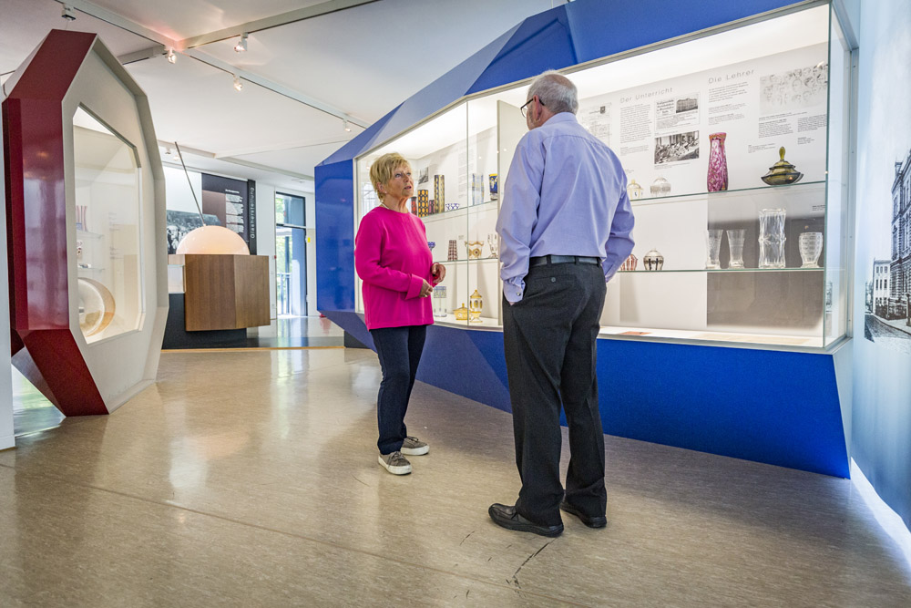 Zwei Besucher sehen sich die Exponate im Glasmuseum an