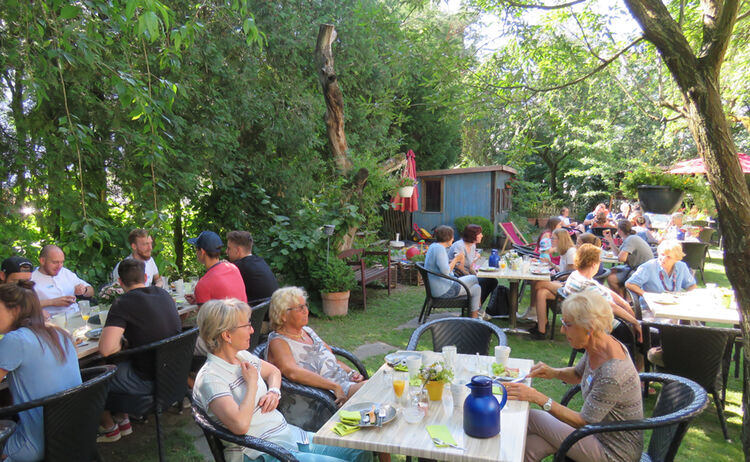 Teilnehmer des fairen Frühstück sitzen im Garten beim Essen
