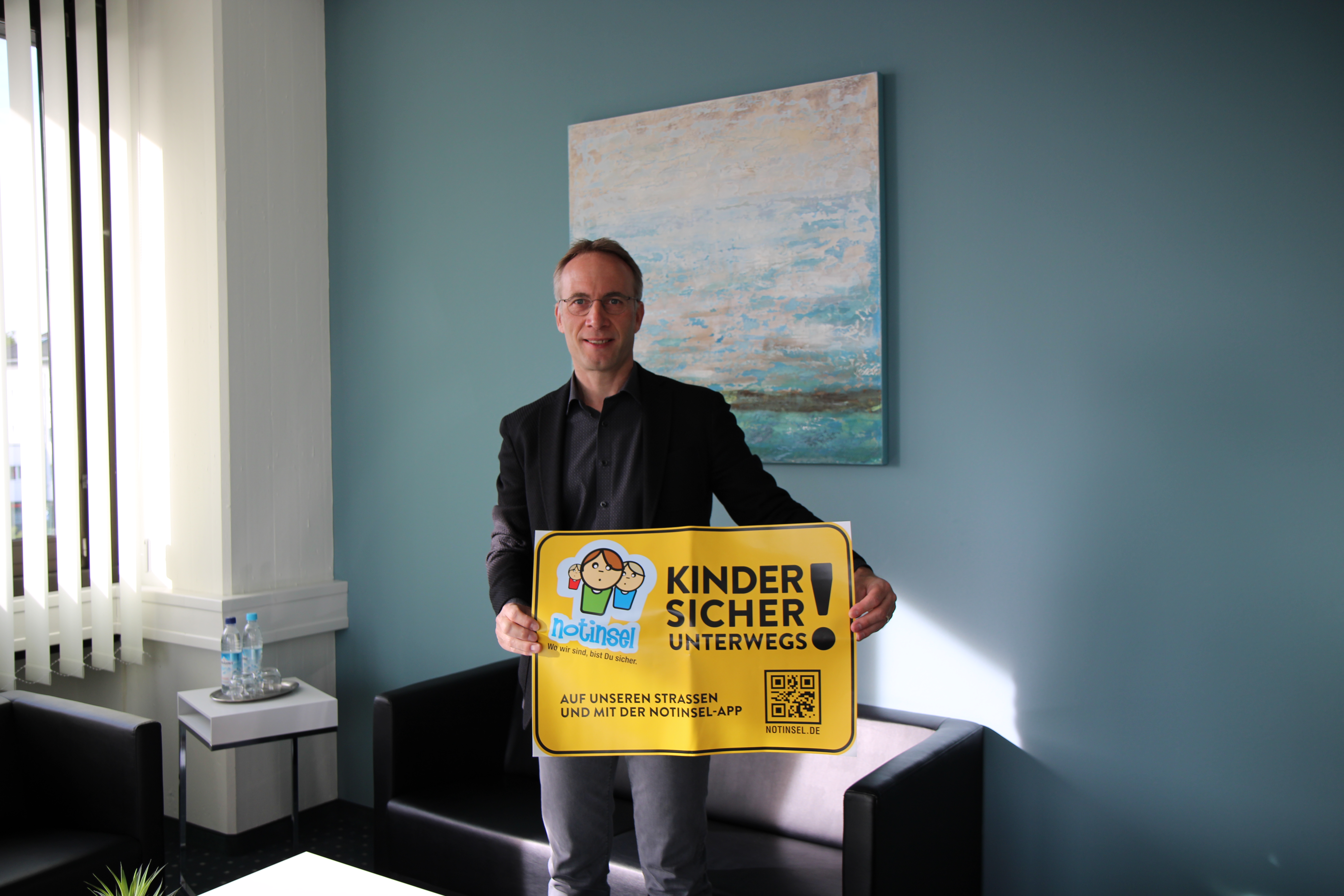 Bürgermeister Robert Pötzsch hält ein Plakat zum Notinsel Projekt in die Höhe