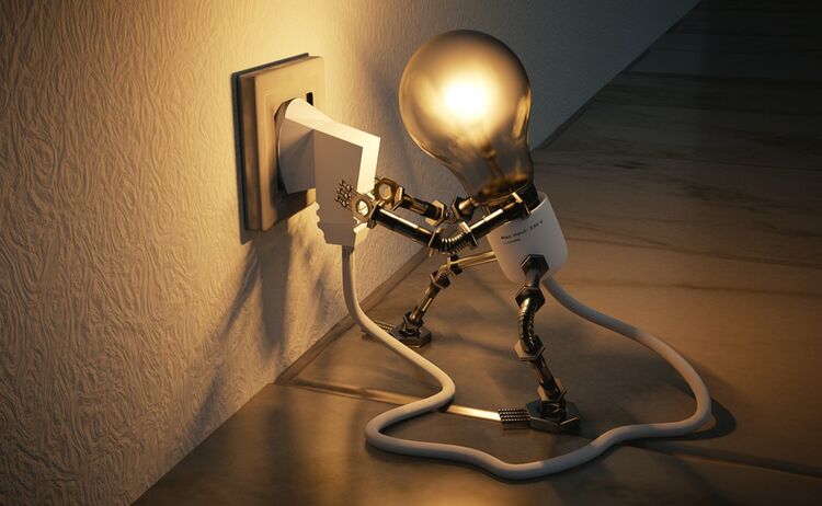 Bild von einer Glühlampe die einen Stecker in die Steckdose steckt. Metapher zur Energiewende: Zum Vergrößern auf Bild klicken