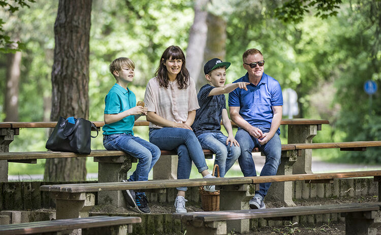 Eine Familie sitzt im Stadtpark auf der Tribüne vor dem Pavillion : Zum Vergrößern auf Bild klicken