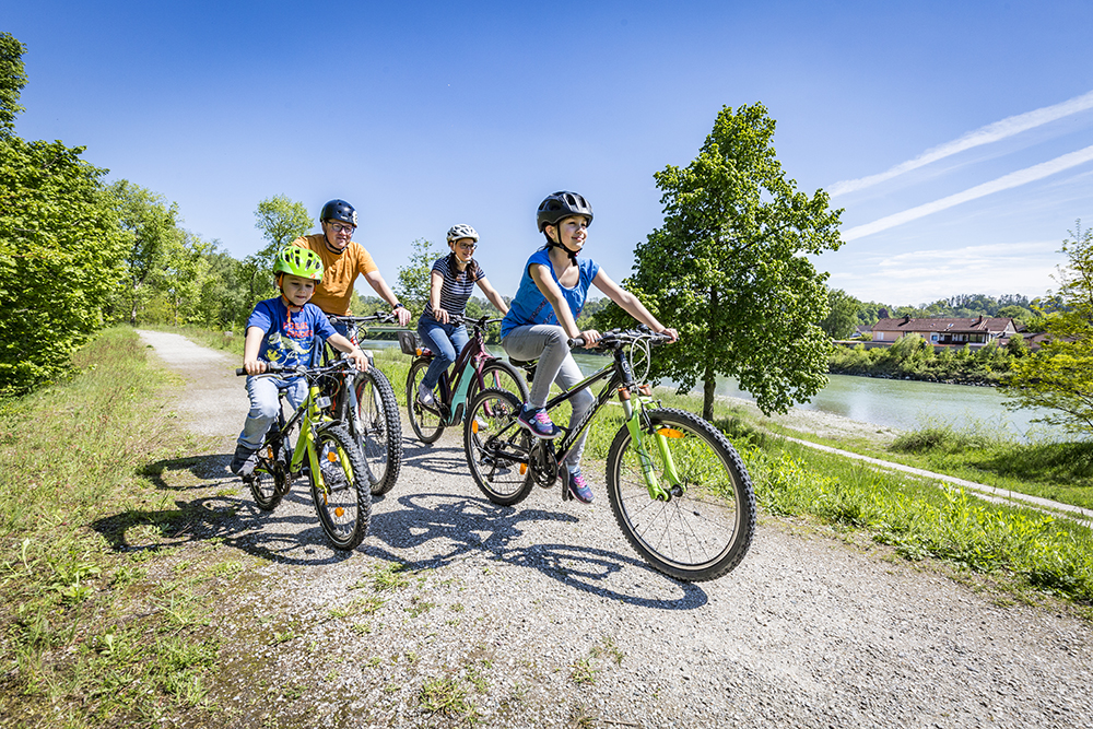 Eine vierköpfige Familie fährt am Inn Fahrrad