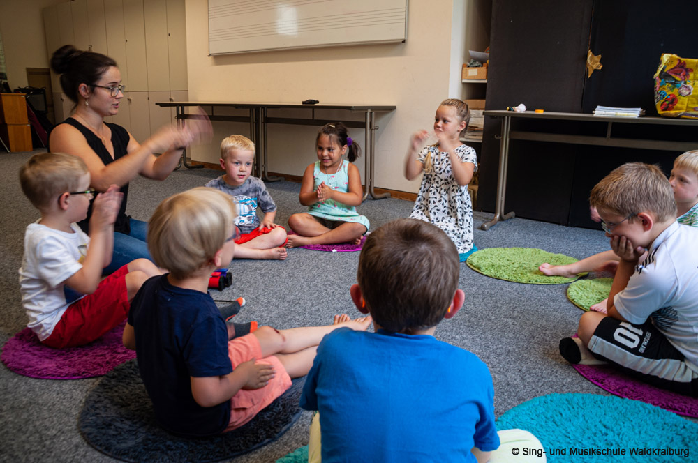 Kinder sitzen bei der Musikalische Früherziehung im Kreis Kinder sitzen bei der Musikalische Früherziehung im Kreis