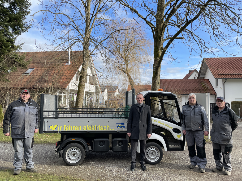 Die Mitarbeiter des Waldfriedhofes und Erster Bürgermeister Robert Pötzsch stehen vor dem neuen E-Fahrzeug des Waldfriedhofes