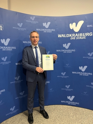 Erster Bürgermeister Robert Pötzsch hält die Fairtrade Urkunde in der Hand