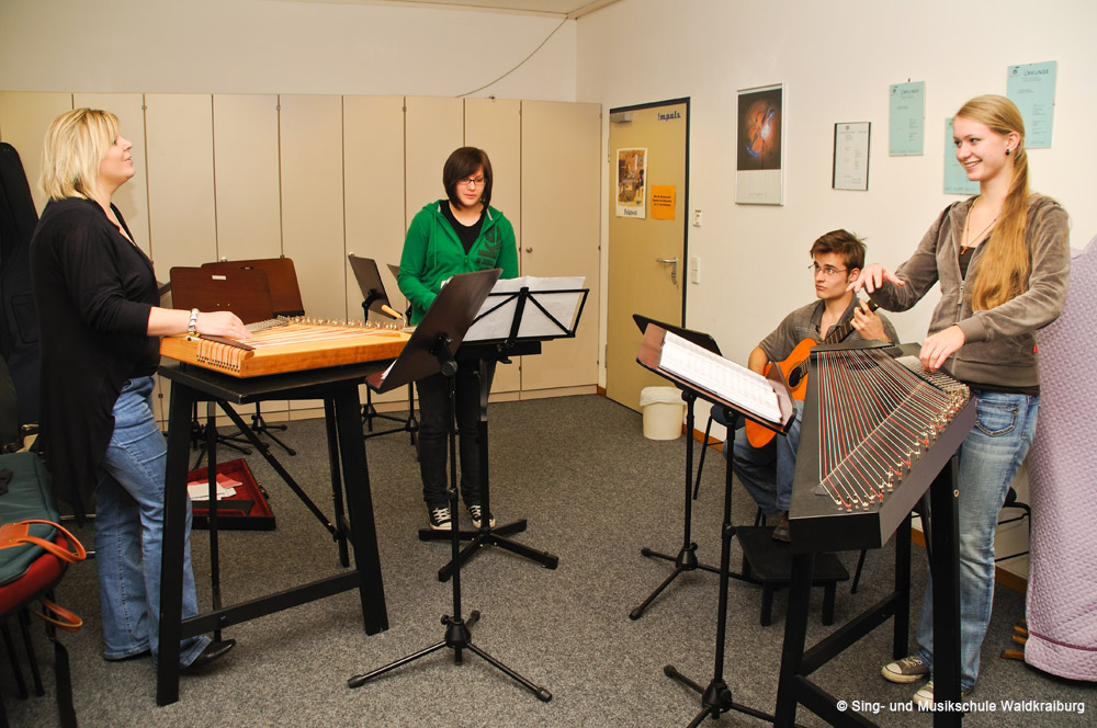 Vier Erwachsene spielen an der Sing- und Musikschule ihre Saiteninstrumente