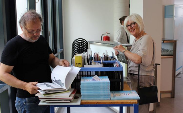 Zwei Besucher stöbern durch eine Bücherbox der Ausstellung Verschwundene Orte: Klick öffnet eine vergrößerte Ansicht