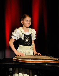 Ein junges Mädchen spielt Zither auf der Bühne